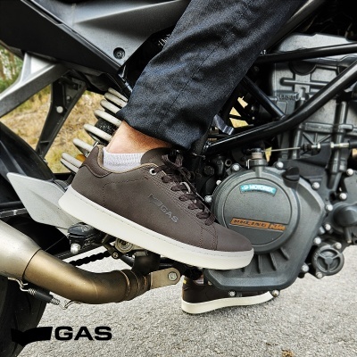 Ténis castanhos GAS com sola branca em pé num descanso de mota preto