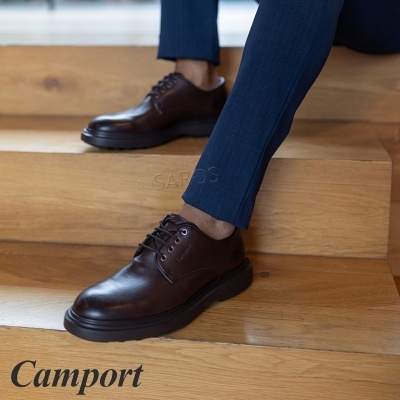 Sapatos de pele castanha com sola preta numas escadas de madeira clara.