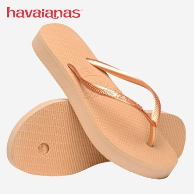 Par de chinelos Havaianas bege com tiras douradas sobre fundo branco