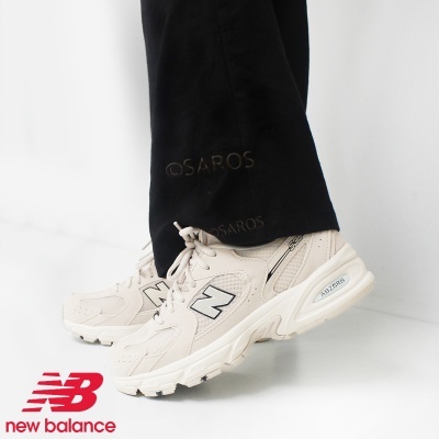 Ténis New Balance bege claro com sola grossa branca e calças pretas
