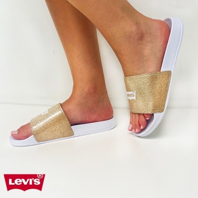Chinelos Levis dourados com base branca em pés femininos