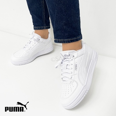 Ténis desportivos Puma brancos usados com calças de ganga escuras