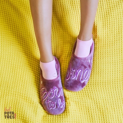 Chinelos cor-de-rosa aveludados com bordado 'Born to be fine' sobre manta amarela