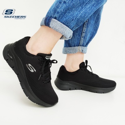 Ténis pretos Skechers com malha e sola preta usados com jeans