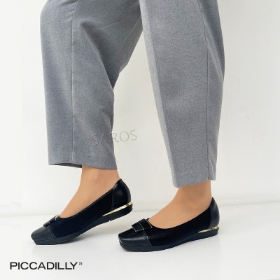 Sapatos pretos rasos com detalhe dourado no salto, usados com calças cinzentas.