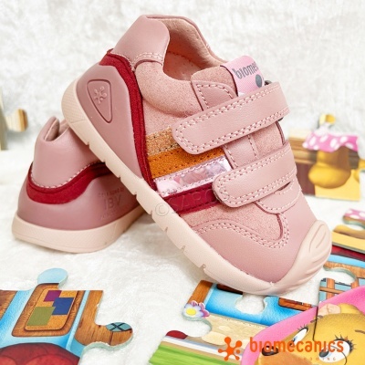 Sapatilhas infantis cor-de-rosa com fechos de velcro e detalhes coloridos sobre puzzle