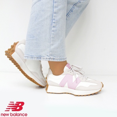 Ténis New Balance branco com detalhes rosa e sola castanha junto a calças de ganga azul clara