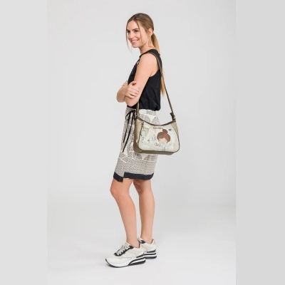 Mulher com bolsa de ombro bege com desenho de rapariga, top preto, saia bege com texto e ténis brancos