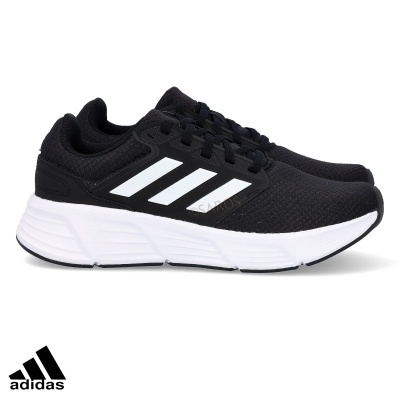 ténis pretos Adidas com riscas brancas e sola branca sobre fundo branco