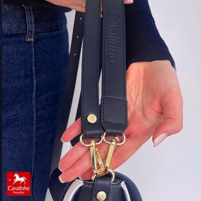Alça preta de couro com fivela dourada e gravação em relevo da marca Cavalinho