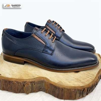 Sapatos masculinos em pele azul escuro com atacadores castanhos sobre base de madeira