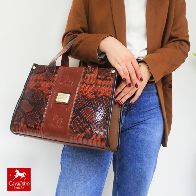 Mala de senhora Cavalinho em pele castanha com padrão de cobra e mulher a segurá-la