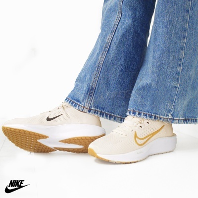 Ténis Nike bege claro com sola castanha e branca usados com jeans azuis.