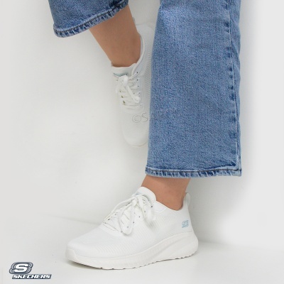 Tênis Skechers brancos com sola espessa e calças de ganga azuis sobre fundo branco