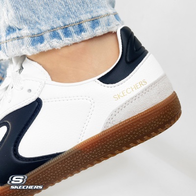 Ténis Skechers brancos e azuis com sola castanha usados com calças de ganga azul claro