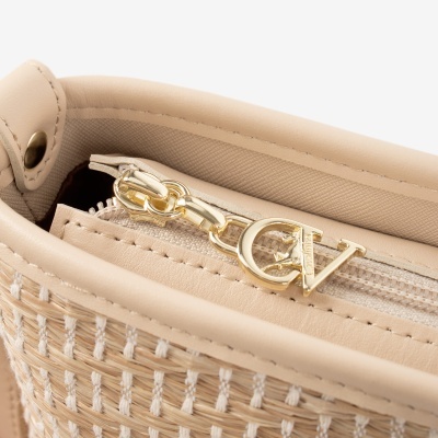 Detalhe de mala bege com fecho e pingente dourado