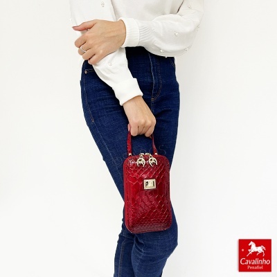 Bolsa de mão vermelha com padrão textura crocodilo segurada por pessoa