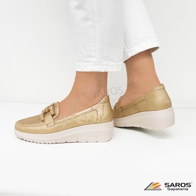 Mocassim bege com sola branca e detalhes perfurados, calça branca, fundo branco