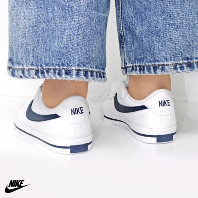 Ténis brancos Nike com logótipo azul escuro e calças de ganga