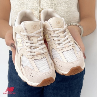 Ténis New Balance bege e branco segurados por uma pessoa