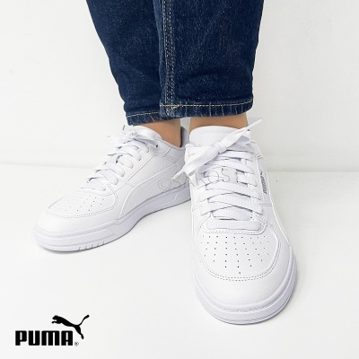 Ténis baixos brancos Puma com atacadores e perfurações, calças de ganga azul escuro