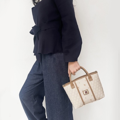 Mala de senhora bege e castanha com padrão acolchoado e logo central