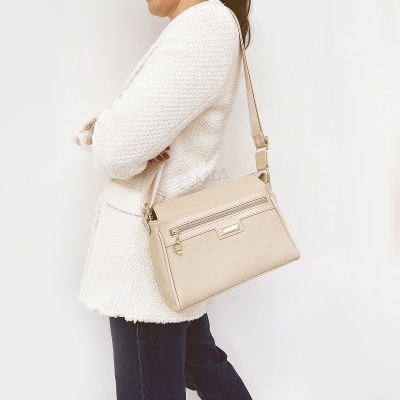 Mulher com mala de ombro bege clara e casaco branco texturizado