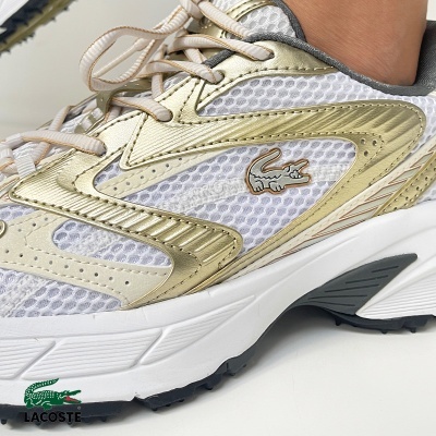 Ténis branco com detalhes dourados e cinzentos e logo Lacoste