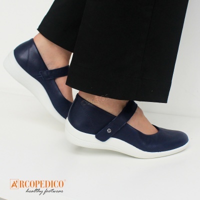 Sapatos de couro azul escuro com sola branca e fecho em tiras, usados por pessoa com calças pretas.