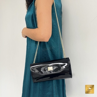 Bolsa preta brilhante com corrente dourada usada por mulher com vestido azul
