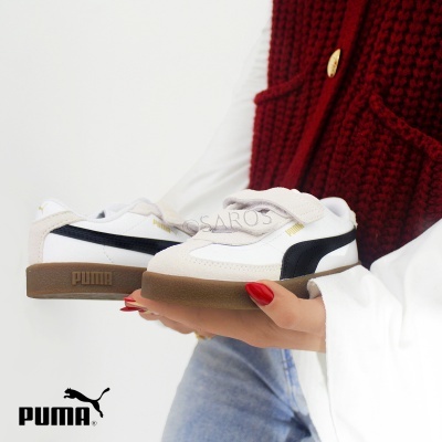 Ténis PUMA infantis branco com detalhes pretos e bege, base castanha, segurados por pessoa com roupa casual.
