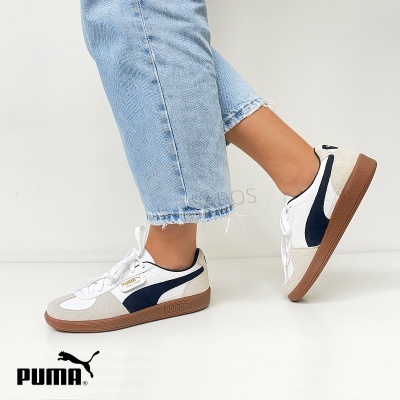 Ténis Puma brancos com detalhe em preto e sola castanha usados com ganga azul clara