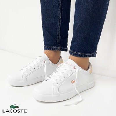 Ténis brancos Lacoste com logótipo rosa e calças de ganga