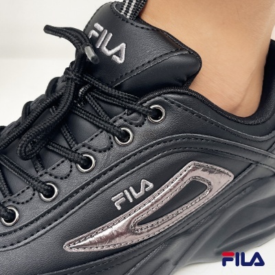 Ténis pretos da FILA com detalhes prateados e cadarços pretos.