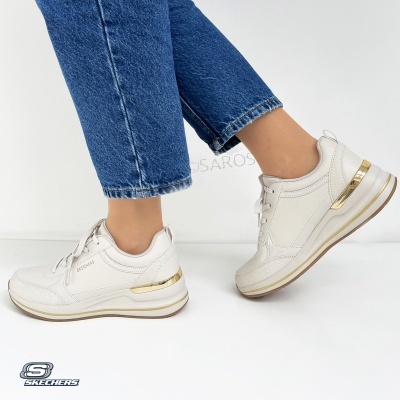 Ténis Skechers brancos com detalhes dourados e sola branca, usados com jeans azuis.