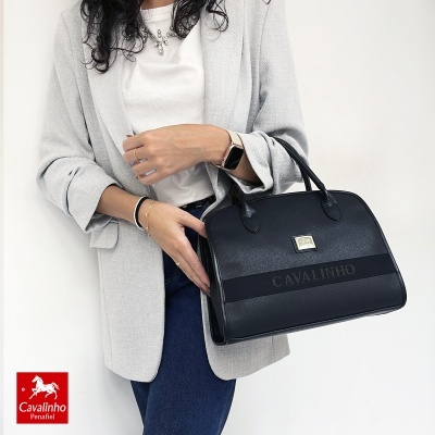 Mala de mão preta Cavalinho com alças e placa dourada, em modelo com blazer cinzento e jeans azuis