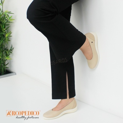 Sapatos sapatilhas bege claro com sola branca usados com calças pretas em fundo branco