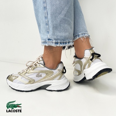 Tênis Lacoste branco e dourado usados com jeans azul claro