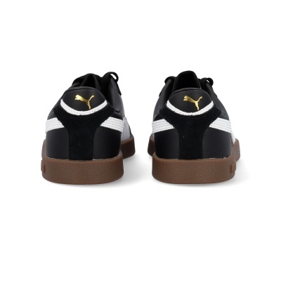 Ténis Puma pretos e brancos com sola castanha vistos de trás