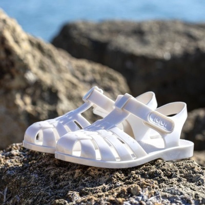 Sandálias de borracha brancas para crianças sobre rochas junto ao mar