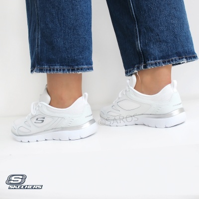 Sapatilhas brancas Skechers com sola espessa e detalhes em relevo, usadas com calças de ganga azuis