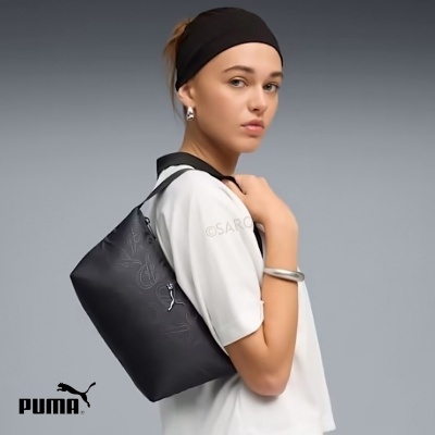 Mulher com mala de ombro preta PUMA em fundo cinza