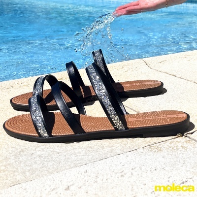 Sandálias femininas pretas com estampado prateado junto a piscina