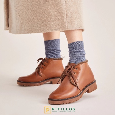 Botas de pele castanha com atacadores e forro de pelo, usadas com meias azul cinzento