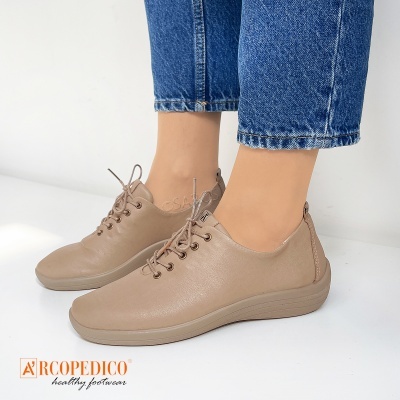 Ténis bege com atacadores em superfície branca com calças de ganga