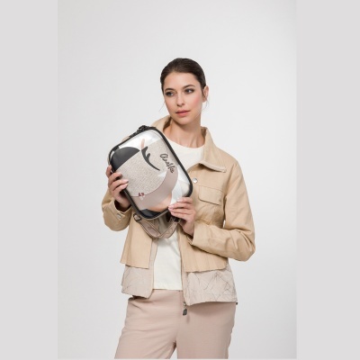 Mulher com casaco bege claro segura bolsa pequena com padrão abstrato