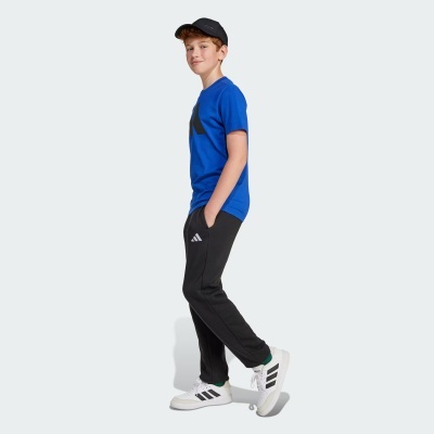 Rapaz jovem com roupa desportiva azul, preta e branca, em fundo claro.