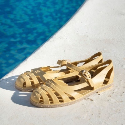 Sandálias femininas amarelas de plástico junto a piscina