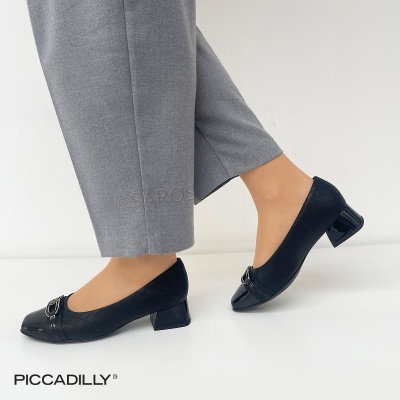 Sapatos pretos de salto médio com calças cinzentas.