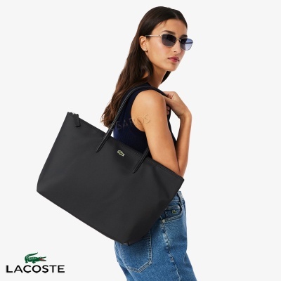 Mulher com mala preta Lacoste e óculos de sol